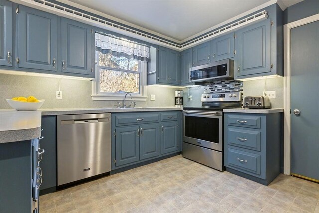 kitchen featuring blue cabinetry, tasteful backsplash, stainless steel appliances, and light countertops