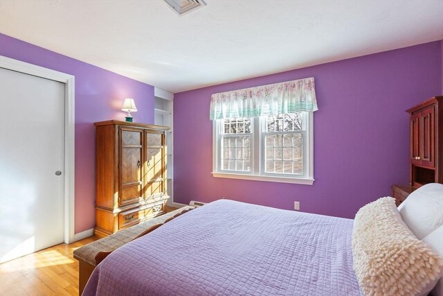 bedroom with light wood-style flooring, a closet, and visible vents