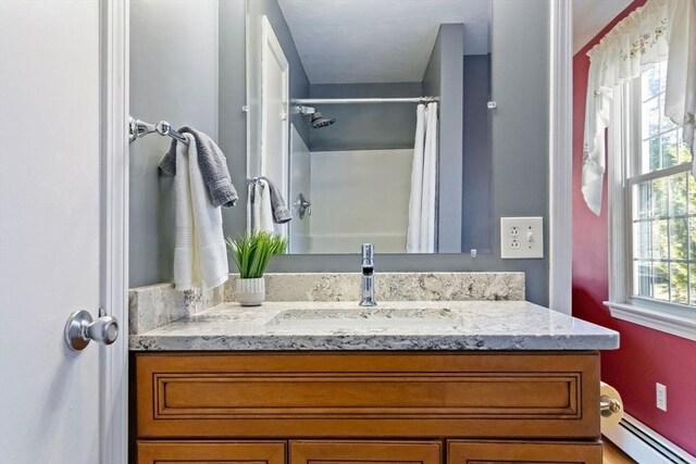 full bathroom featuring a shower with shower curtain, a baseboard heating unit, and vanity