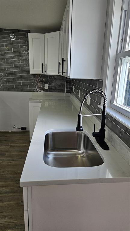 kitchen with decorative backsplash, sink, white cabinets, and dark wood-type flooring