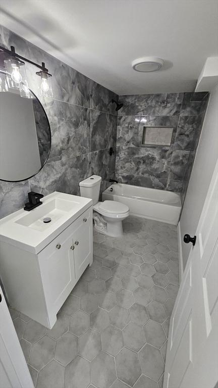 full bathroom featuring tile patterned floors, tile walls, toilet, vanity, and shower / bath combination