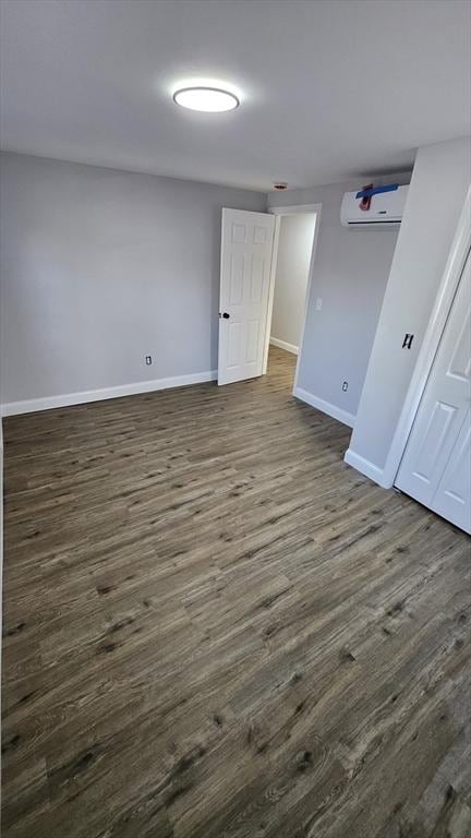 unfurnished room with a wall unit AC and dark hardwood / wood-style flooring