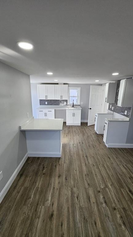 kitchen with decorative backsplash, white cabinets, dark hardwood / wood-style floors, and kitchen peninsula