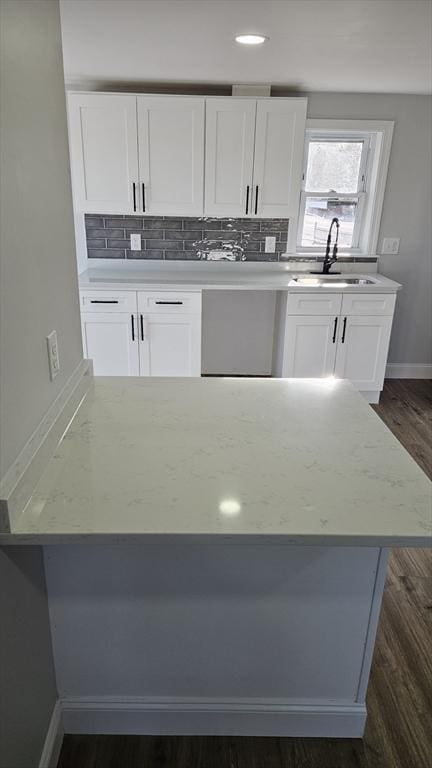 kitchen with sink, white cabinets, dark wood-type flooring, light stone countertops, and decorative backsplash