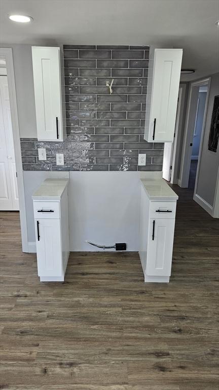 kitchen with backsplash, white cabinetry, and dark wood-type flooring