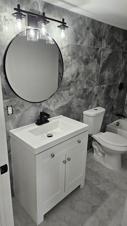 bathroom featuring vanity, toilet, and tile walls