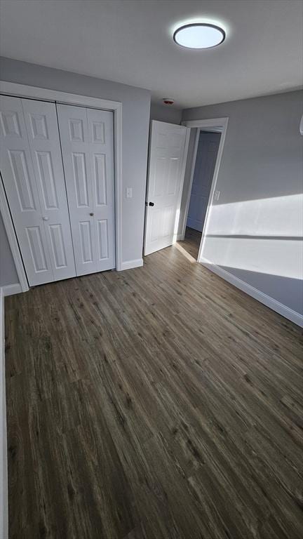 unfurnished bedroom with dark wood-type flooring and a closet