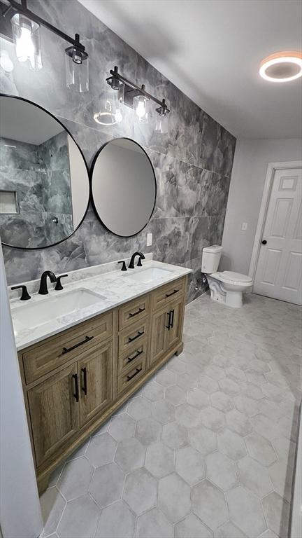 bathroom with toilet, vanity, and tile walls