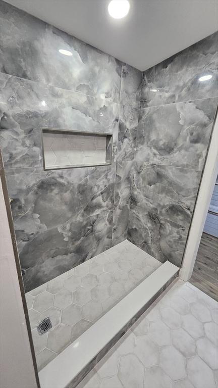 bathroom with tiled shower, tile walls, and tile patterned flooring