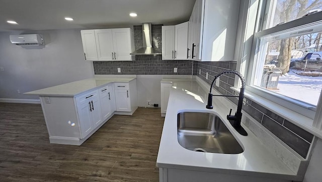 kitchen featuring white cabinetry, wall chimney range hood, sink, a wall mounted AC, and dark hardwood / wood-style floors