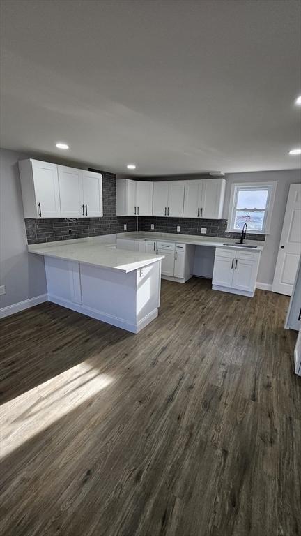 kitchen with sink, white cabinets, kitchen peninsula, and dark hardwood / wood-style flooring