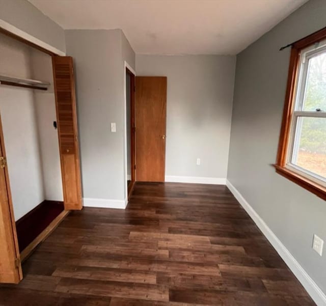 unfurnished bedroom with a closet and dark hardwood / wood-style floors