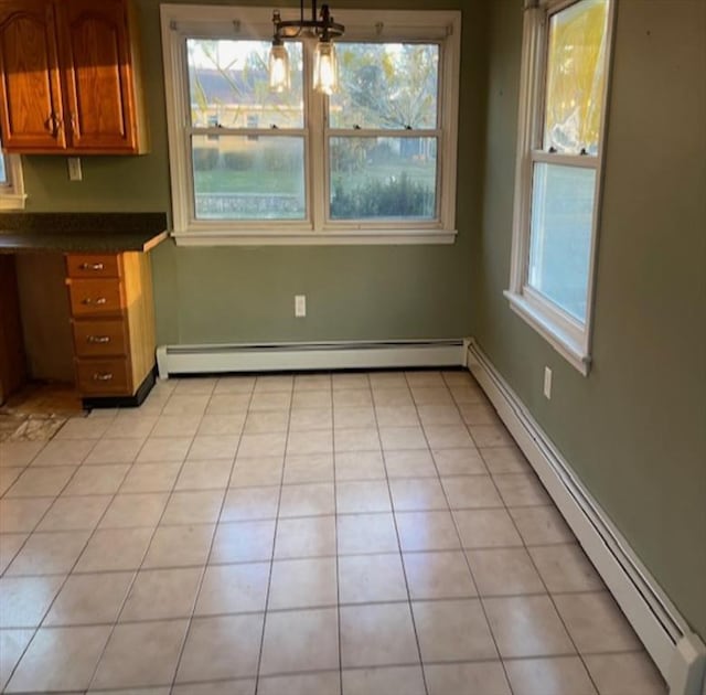 unfurnished dining area with light tile patterned floors, baseboard heating, and a healthy amount of sunlight