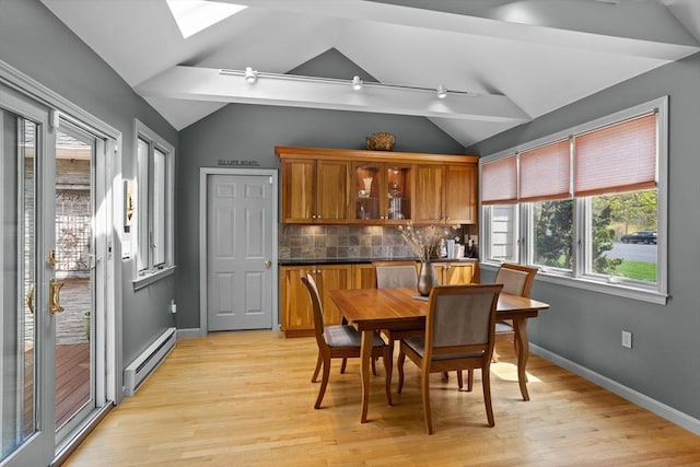 dining area featuring light wood-style floors, baseboards, a baseboard heating unit, and lofted ceiling with skylight
