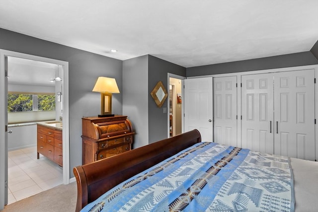 bedroom with light tile patterned floors, baseboards, two closets, connected bathroom, and light carpet