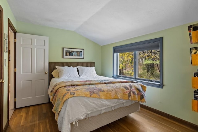 bedroom featuring baseboards, vaulted ceiling, and wood finished floors