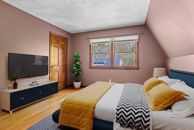 bedroom featuring vaulted ceiling and light wood-style flooring