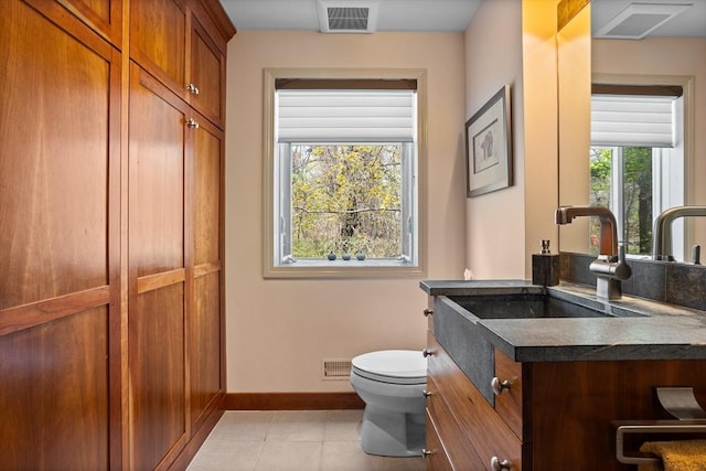 half bath featuring baseboards, vanity, toilet, and visible vents