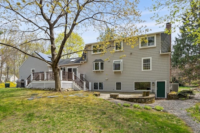 rear view of property featuring central AC, a wooden deck, a chimney, a yard, and stairway