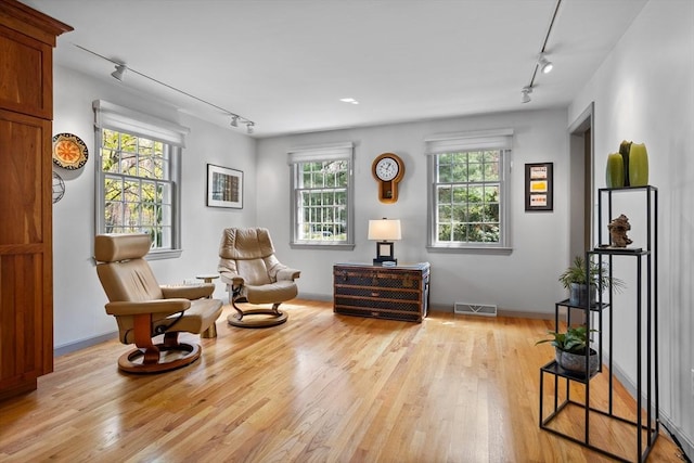 living area featuring track lighting, light wood-style flooring, and visible vents