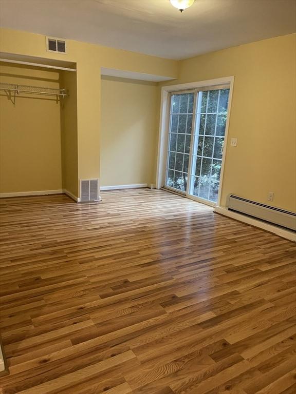 24A Outlook Dr Unit A, Worcester, MA 01602 - unfurnished bedroom with wood finished floors, access to exterior, baseboard heating, and a closet