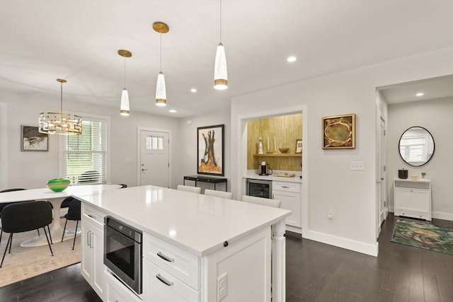 16 Primrose Ln Unit 16, Ipswich, MA 01938 - kitchen with stainless steel microwave, dark wood-style floors, light countertops, white cabinetry, and a kitchen island