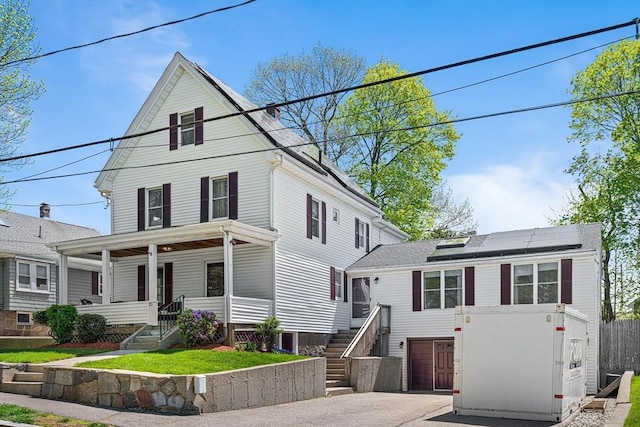 view of front of property with roof mounted solar panels, fence, a porch, and stairway