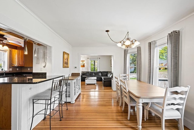 dining room featuring an inviting chandelier, plenty of natural light, ornamental molding, and light wood-style floors