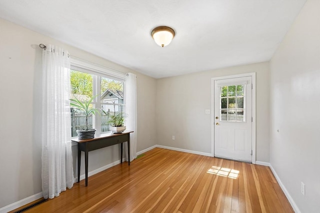 doorway to outside featuring plenty of natural light, light wood-style floors, and baseboards