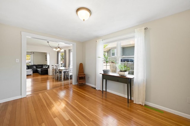 interior space with light wood-type flooring, baseboards, and a notable chandelier