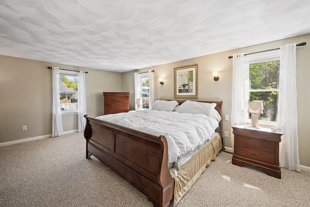 bedroom featuring baseboards, light colored carpet, and multiple windows