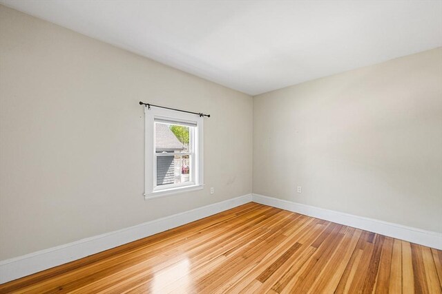 spare room with baseboards and light wood finished floors