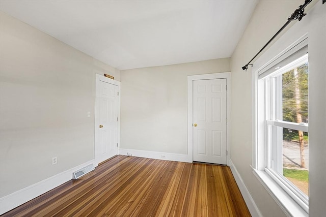 spare room with baseboards, visible vents, plenty of natural light, and wood finished floors