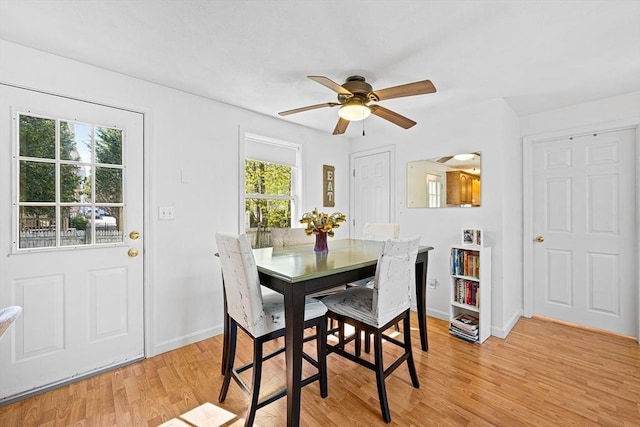 dining room featuring baseboards, plenty of natural light, a ceiling fan, and light wood-type flooring