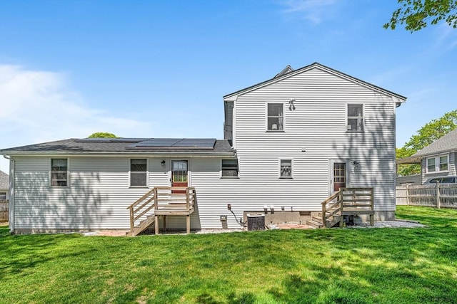 back of house with a lawn, central air condition unit, fence, and solar panels