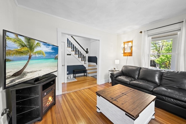 living area featuring stairs, ornamental molding, and light wood finished floors