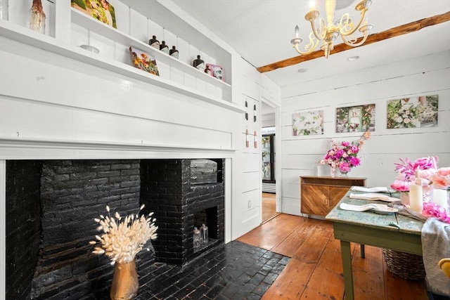 interior space featuring beam ceiling, hardwood / wood-style flooring, a notable chandelier, and a fireplace with flush hearth