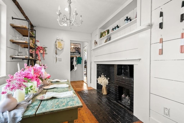 living area featuring a fireplace with flush hearth, an inviting chandelier, and wood-type flooring