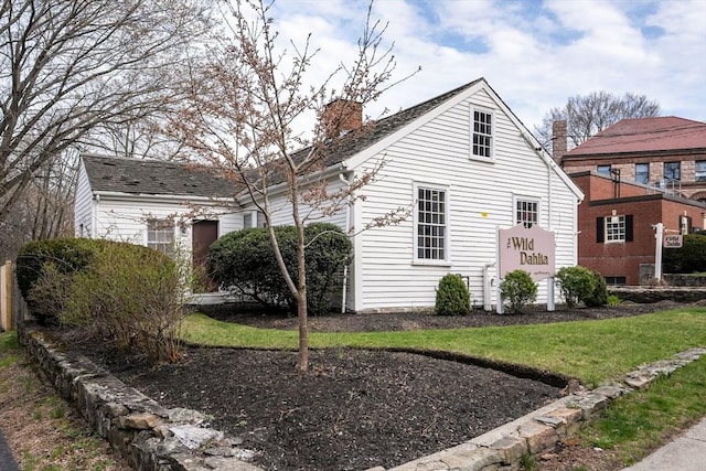 view of side of property featuring a lawn and a chimney