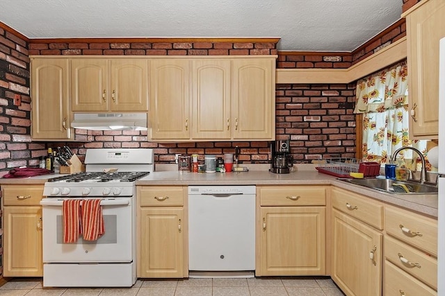 kitchen with white appliances, under cabinet range hood, a sink, a textured ceiling, and light brown cabinets