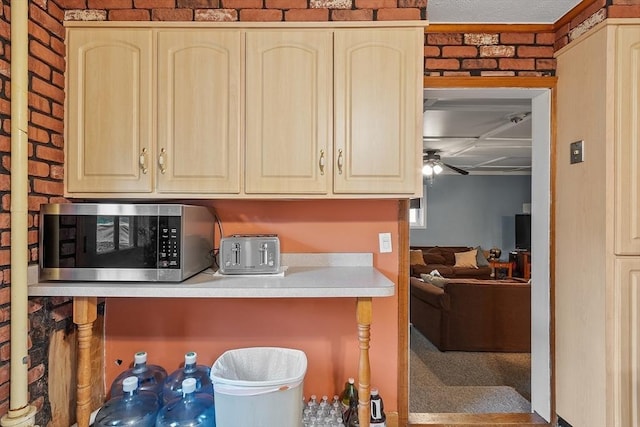 kitchen featuring stainless steel microwave, ceiling fan, light countertops, light brown cabinetry, and cream cabinetry
