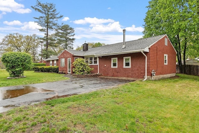 rear view of house featuring a chimney, asphalt driveway, and a shingled roof