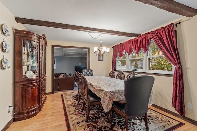 dining room with beam ceiling, light wood finished floors, a chandelier, and baseboards