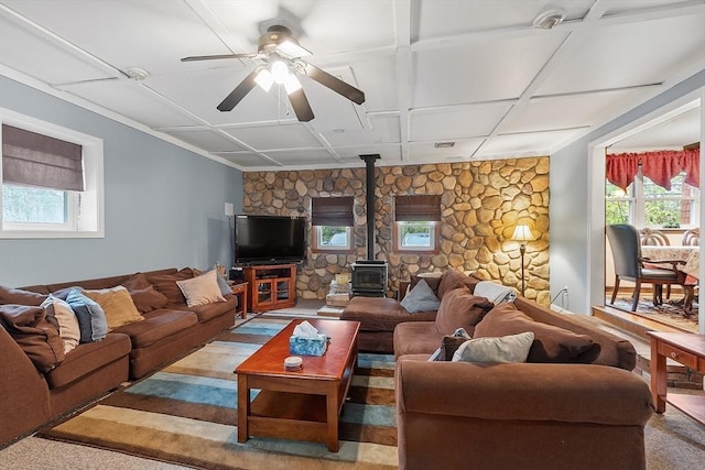 living area with a wood stove, plenty of natural light, ceiling fan, and coffered ceiling