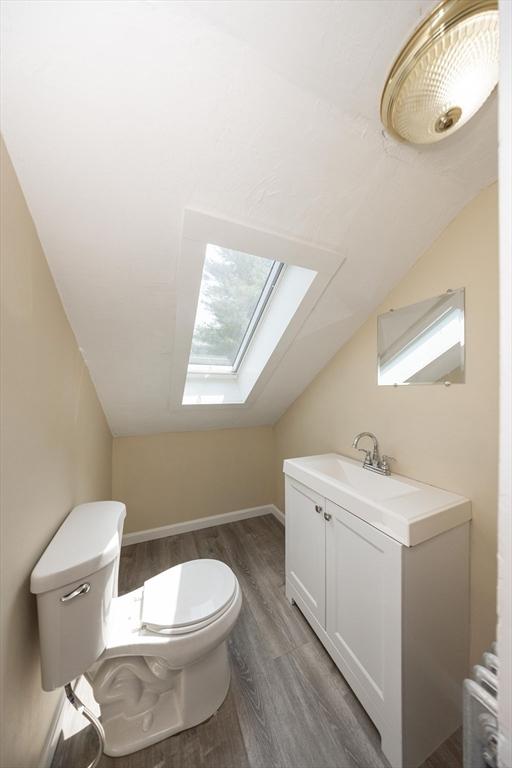 139 Endicott St, Worcester, MA 01610 - half bathroom featuring a skylight, toilet, wood finished floors, vanity, and lofted ceiling