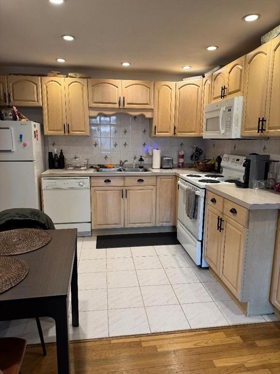 kitchen featuring light brown cabinets, a sink, white appliances, light countertops, and decorative backsplash