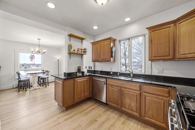 kitchen featuring appliances with stainless steel finishes, decorative light fixtures, sink, kitchen peninsula, and light wood-type flooring