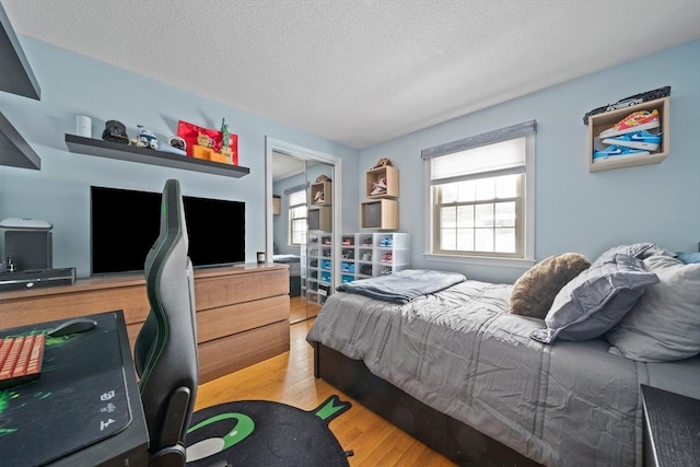 bedroom featuring light wood finished floors and a textured ceiling