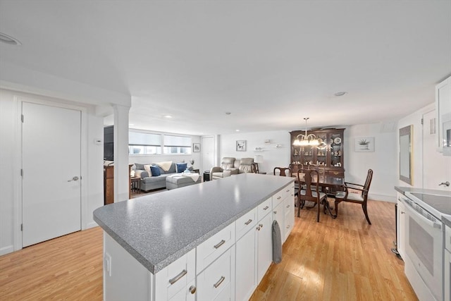 kitchen featuring electric range, light wood-type flooring, a kitchen island, and white cabinetry