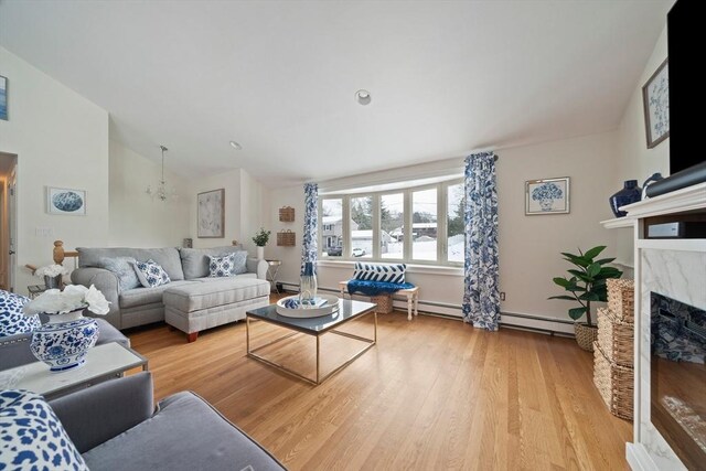 living area featuring lofted ceiling, light wood-type flooring, and a high end fireplace